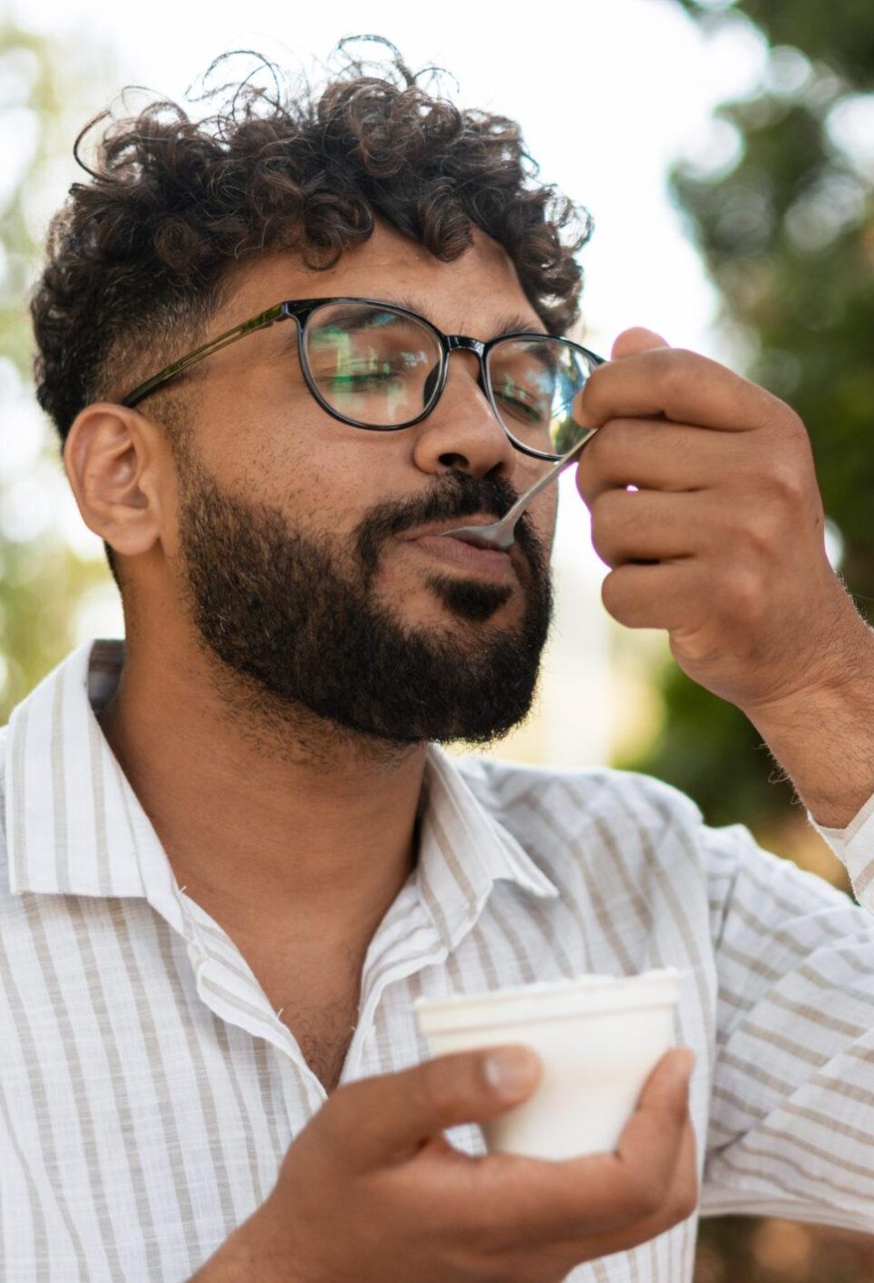 Young man enjoying a tasty dessert outdoors in a park Young man enjoying a tasty dessert outdoors in a park