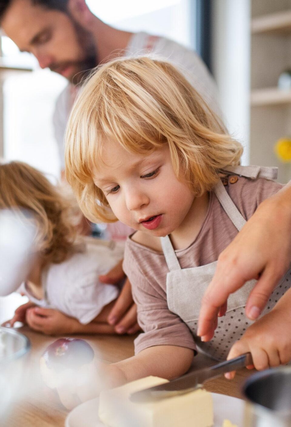 Young family with two small children indoors in kitchen, preparing food. Young family with two small children indoors in kitchen, preparing food.