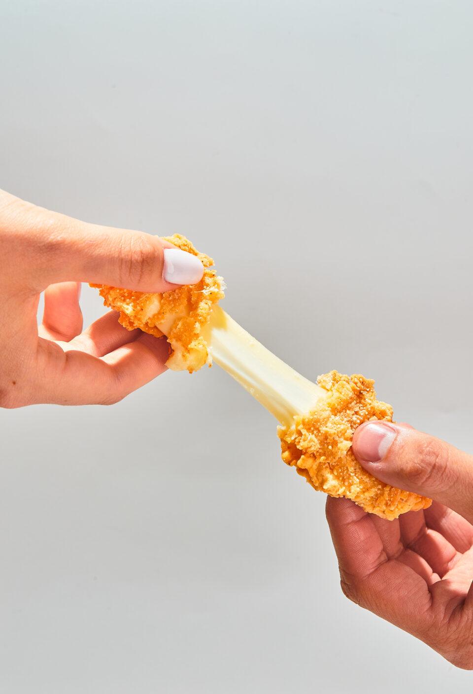 Crispy cheese fried breaded mozzarella cheese sticks stretch two hands Crispy cheese fried breaded mozzarella cheese sticks stretch two hands